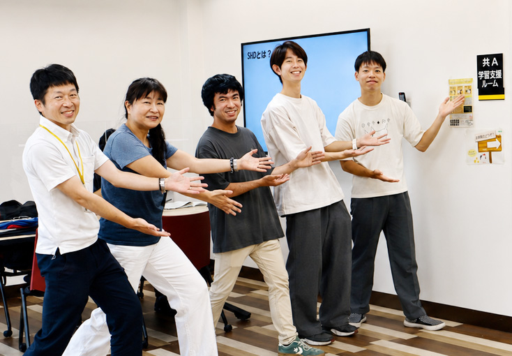 学習支援ルームの前でポーズをとるスタッフと学生